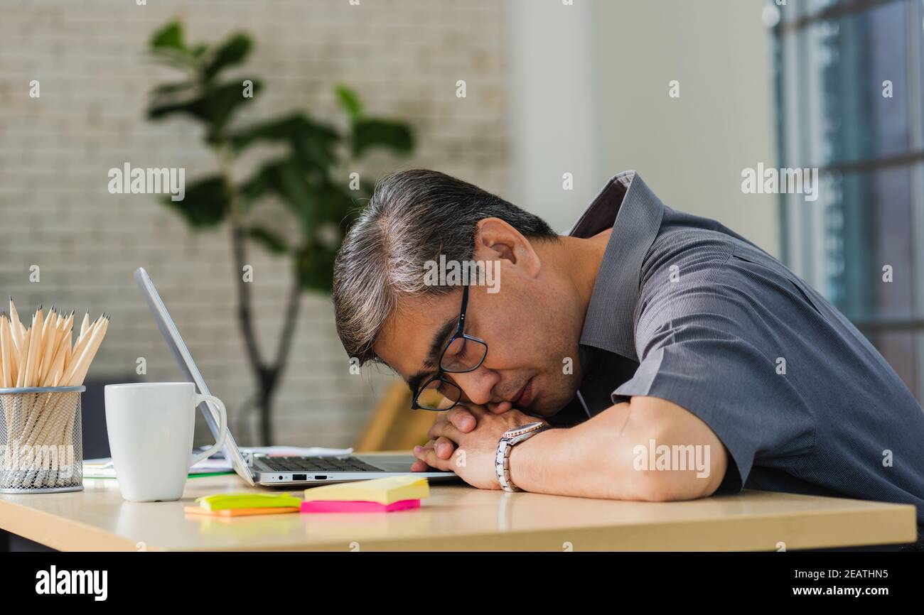 businessman tired overworked he sleeping over a laptop computer Stock Photo