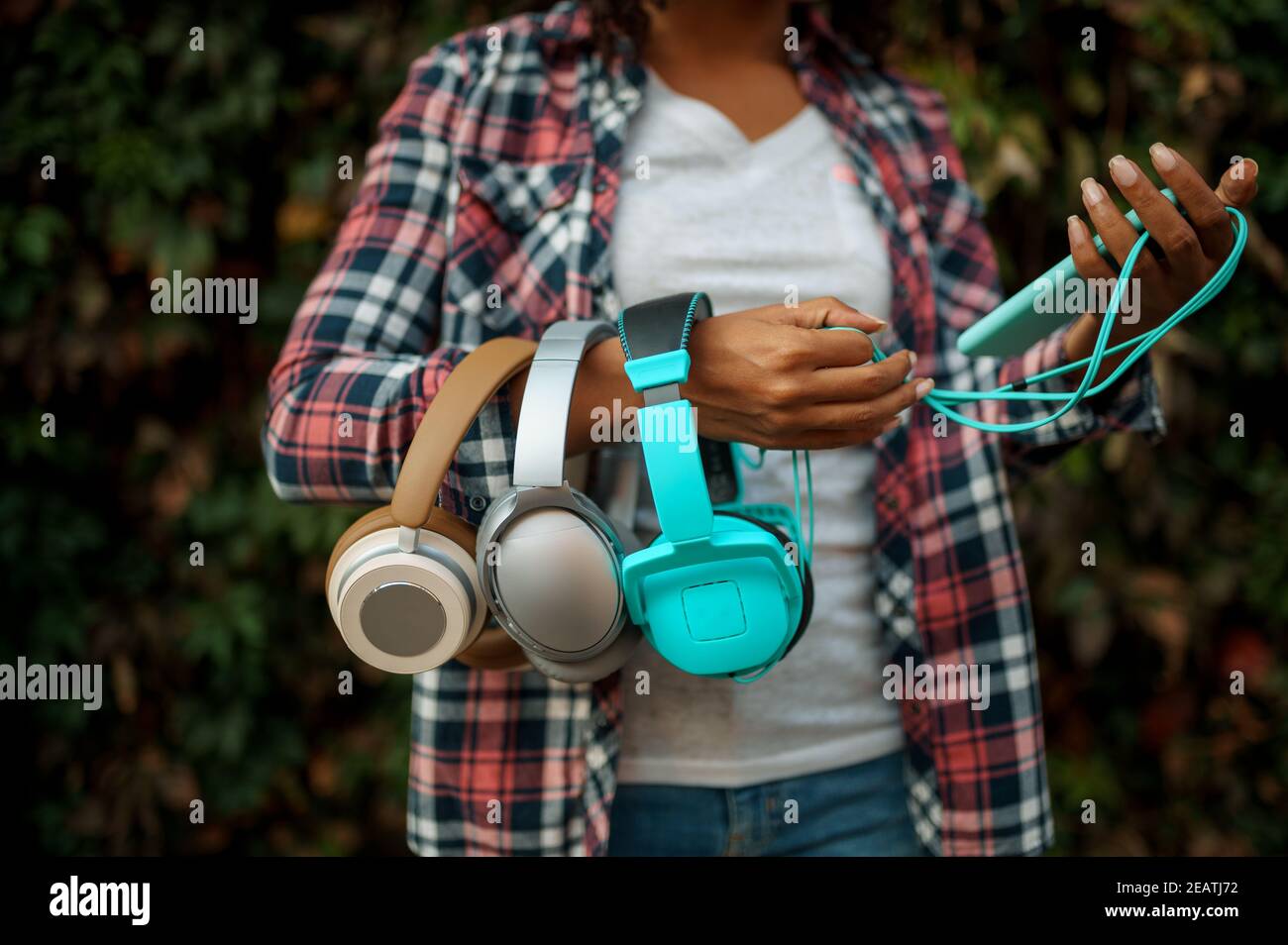 Female music fan holds headphones in summer park Stock Photo