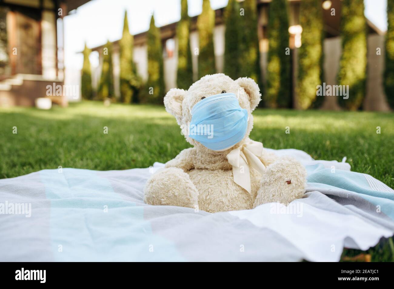 Teddy bear in protection mask sitting on a blanket Stock Photo