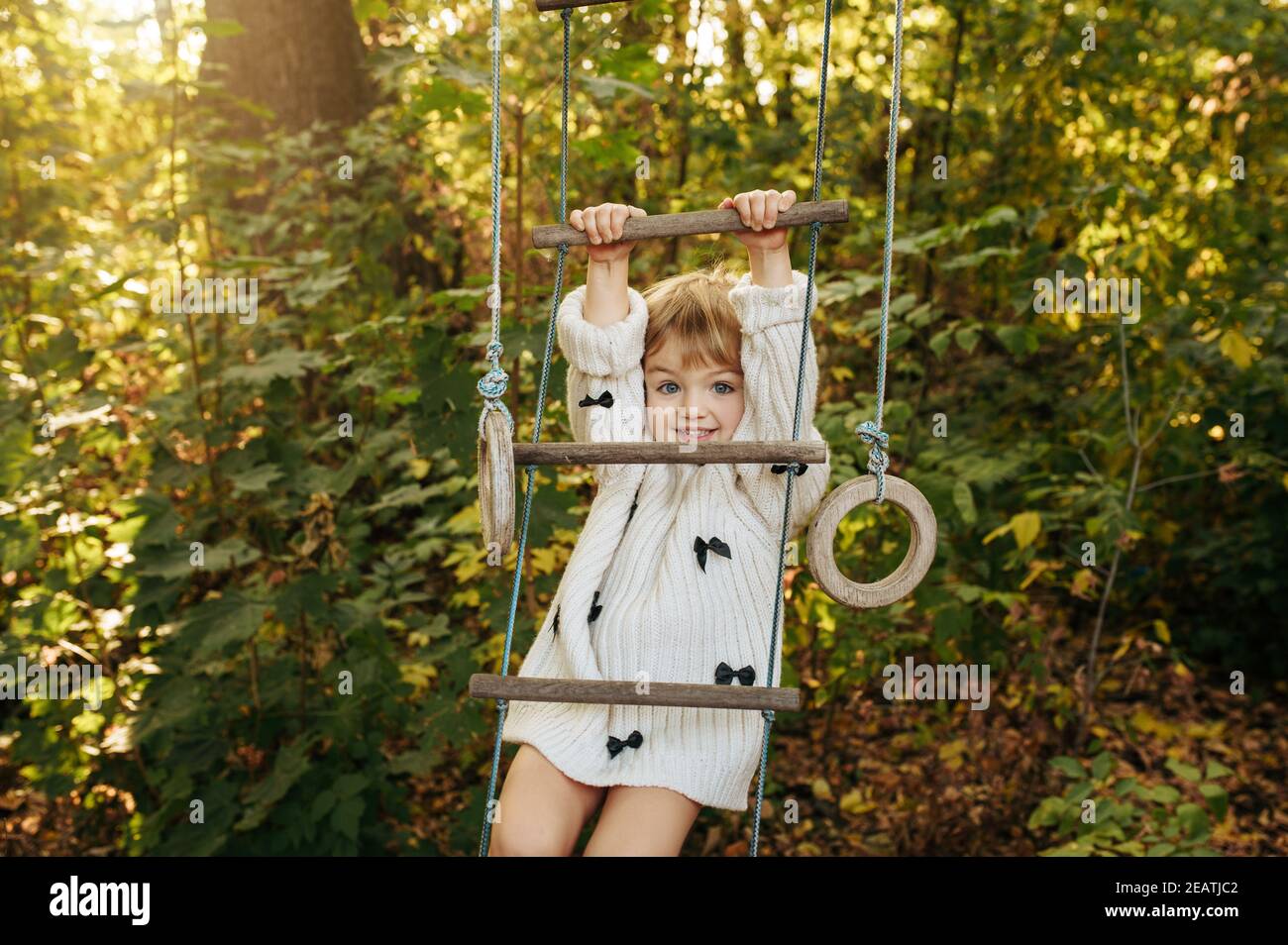 Little girl climbs by rope ladder in the garden Stock Photo