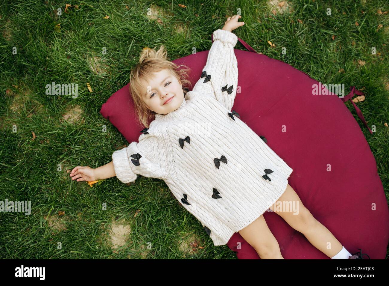 Little girl lying on the grass in the garden Stock Photo