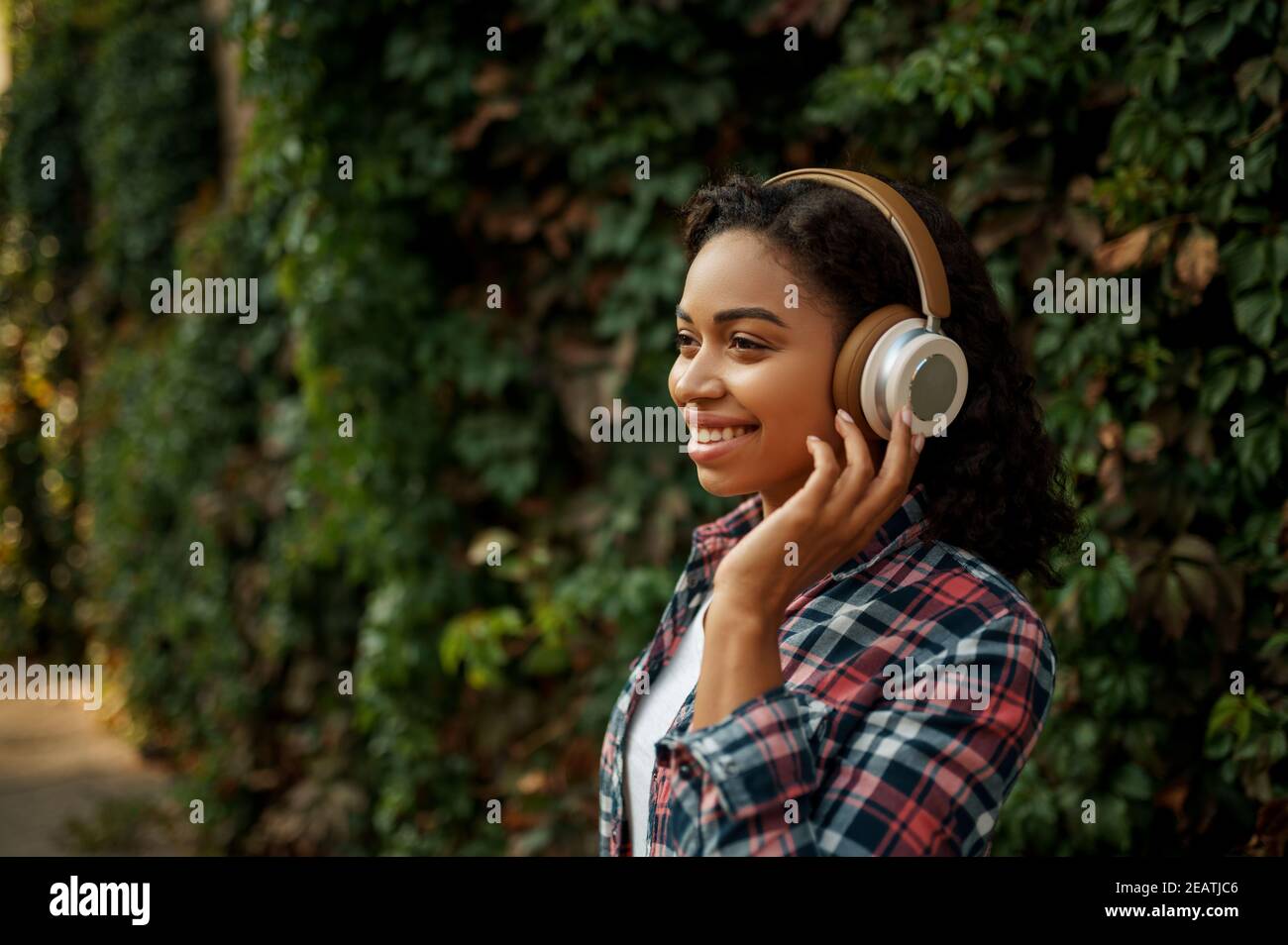 Woman in headphones listening to music in park Stock Photo