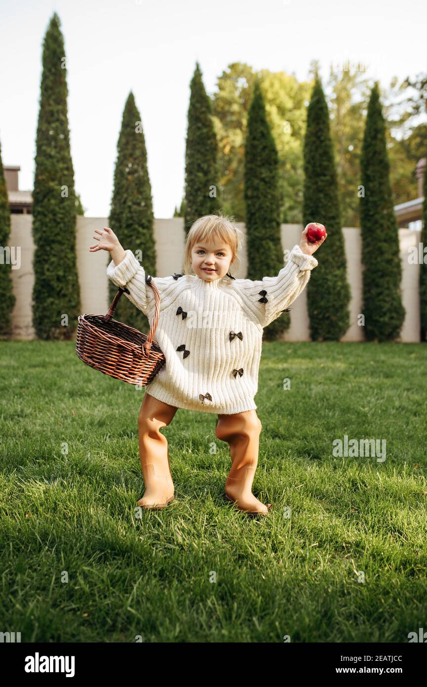 Cheerful kid with basket play in the garden Stock Photo