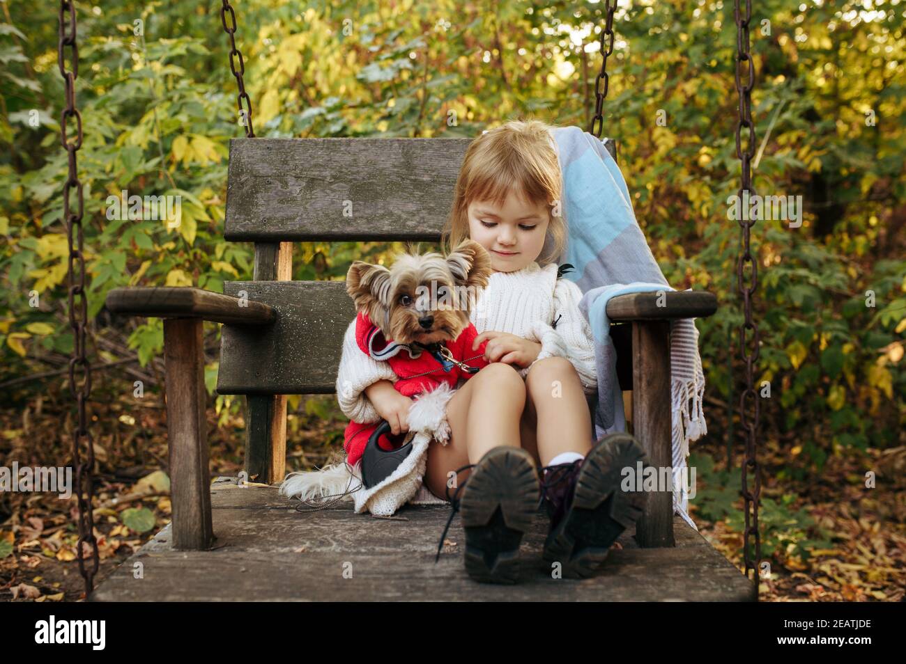 Kid with dog are sitting in big wooden chair Stock Photo