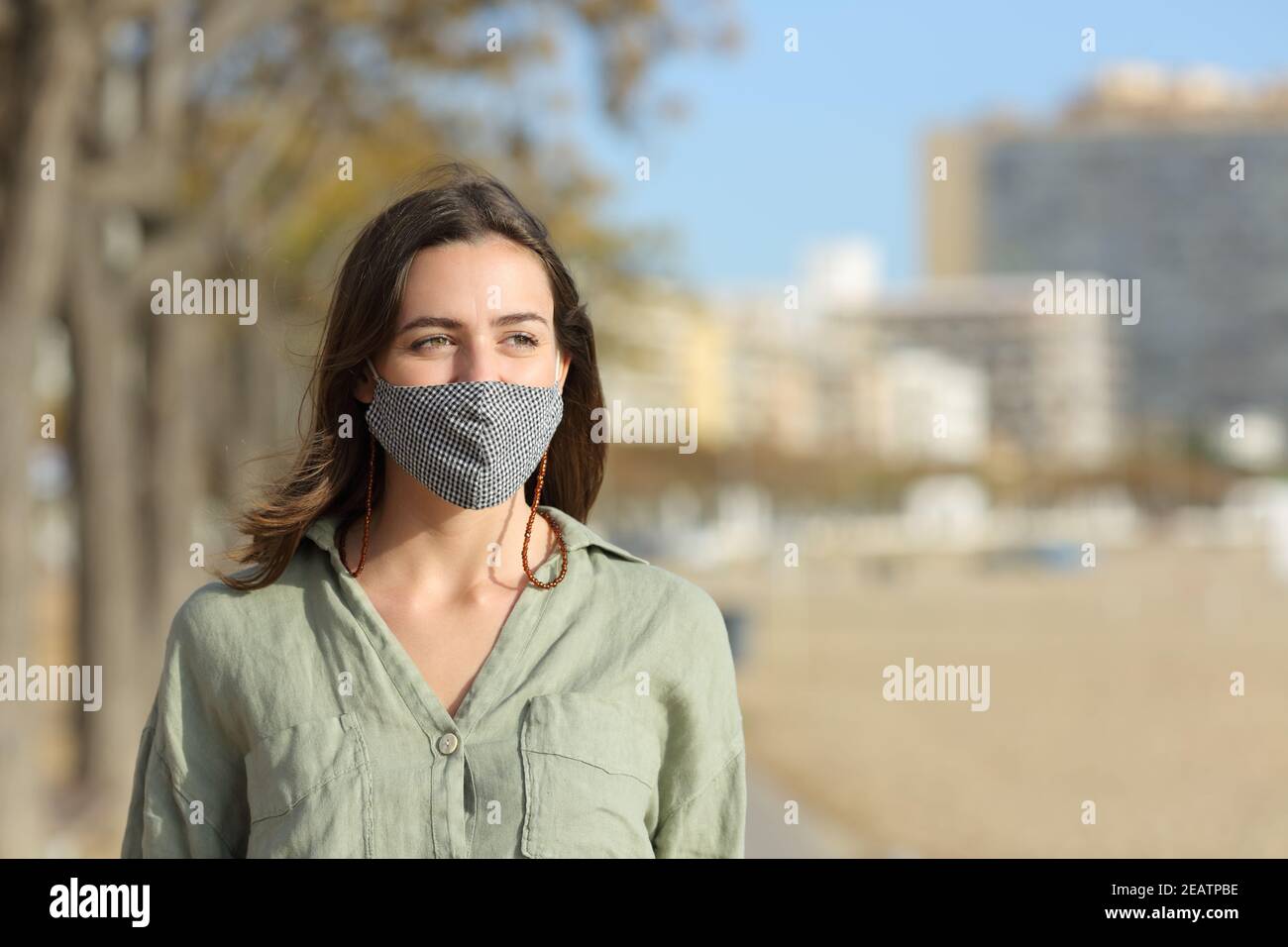 Happy woman walking wearing mask due covid on the beach Stock Photo