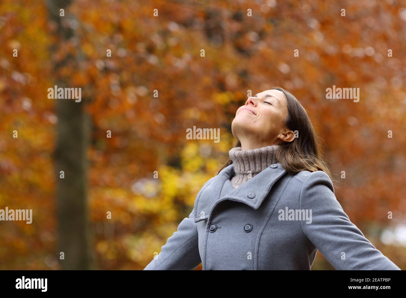 Middle age female breathing fresh air in a forest in fall Stock Photo