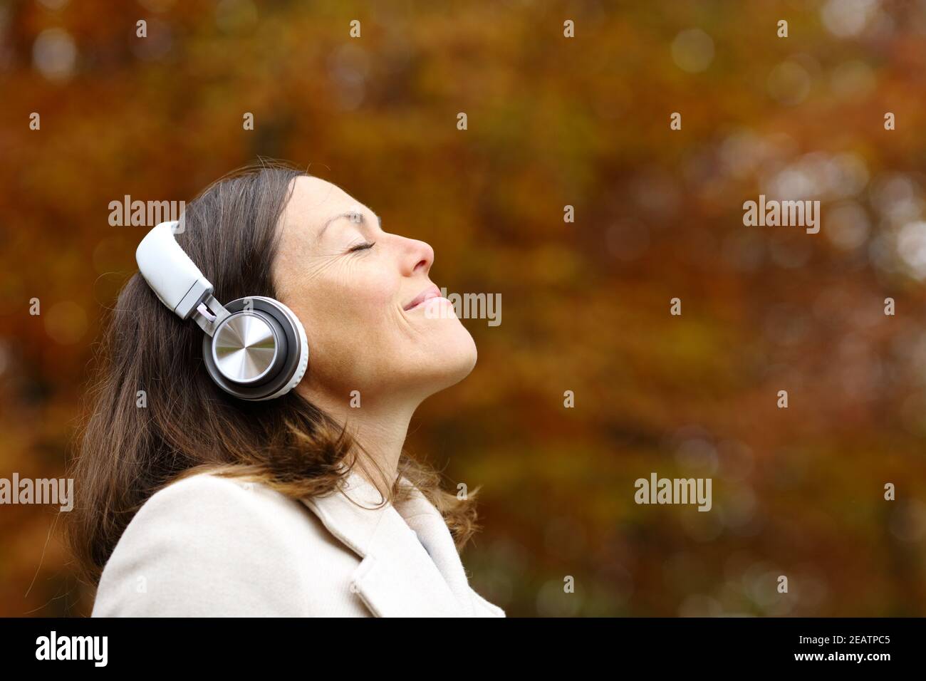 Adult woman breathing fresh air with headphones in autumn Stock Photo