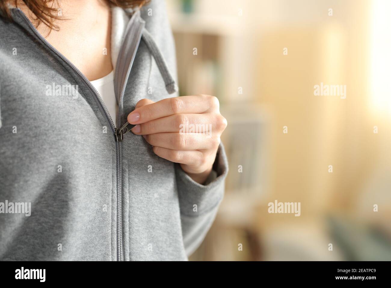 Woman hand dressing closing zipper of hoodie at home Stock Photo