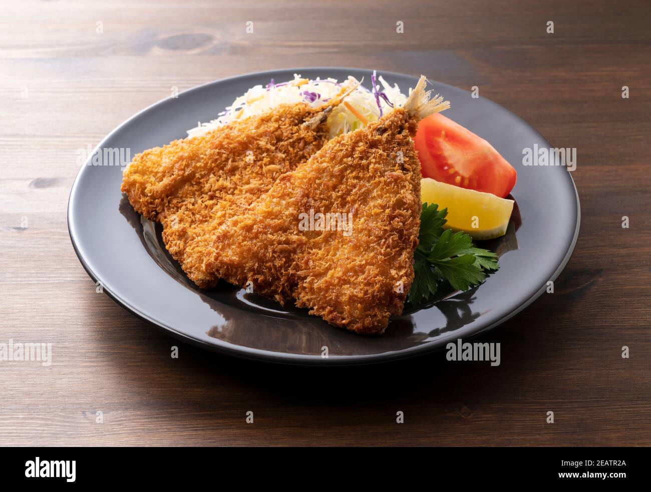 Fried horse mackerel served on a plate on a wooden background Stock Photo