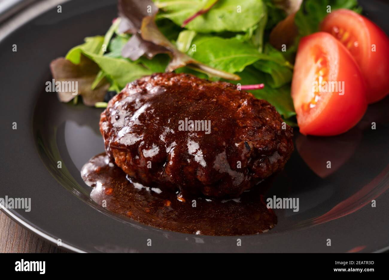 Hamburger with demiglace sauce served on a plate placed on the table