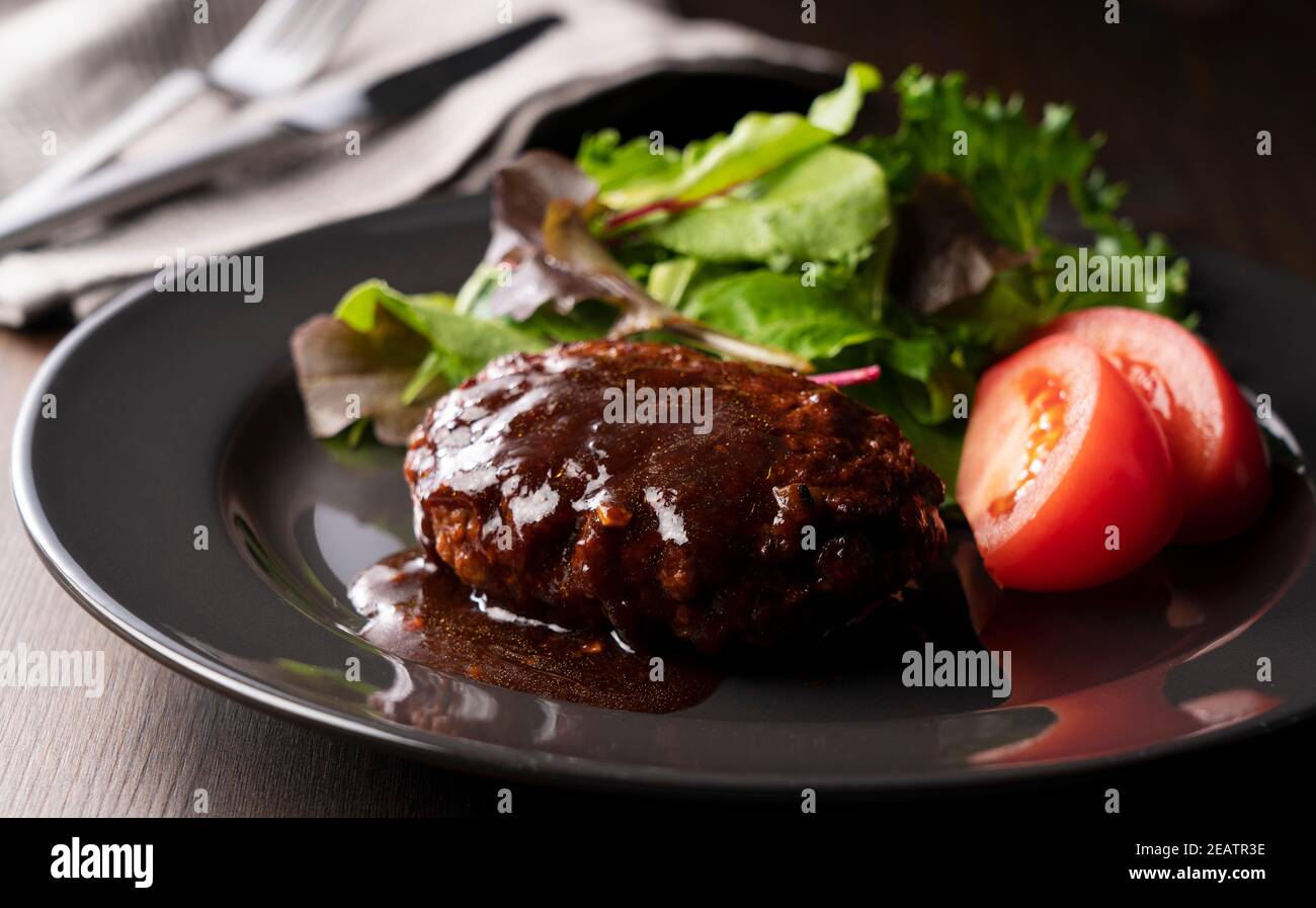 Hamburger with demiglace sauce served on a plate placed on the table