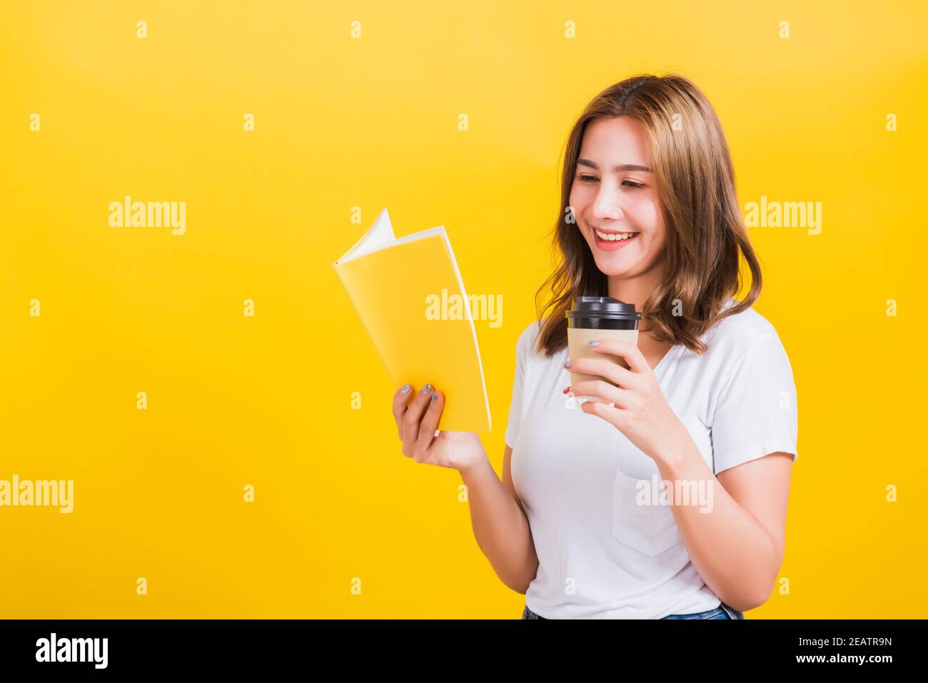 young woman holding drinking take away cup coffee paper and reading book Stock Photo