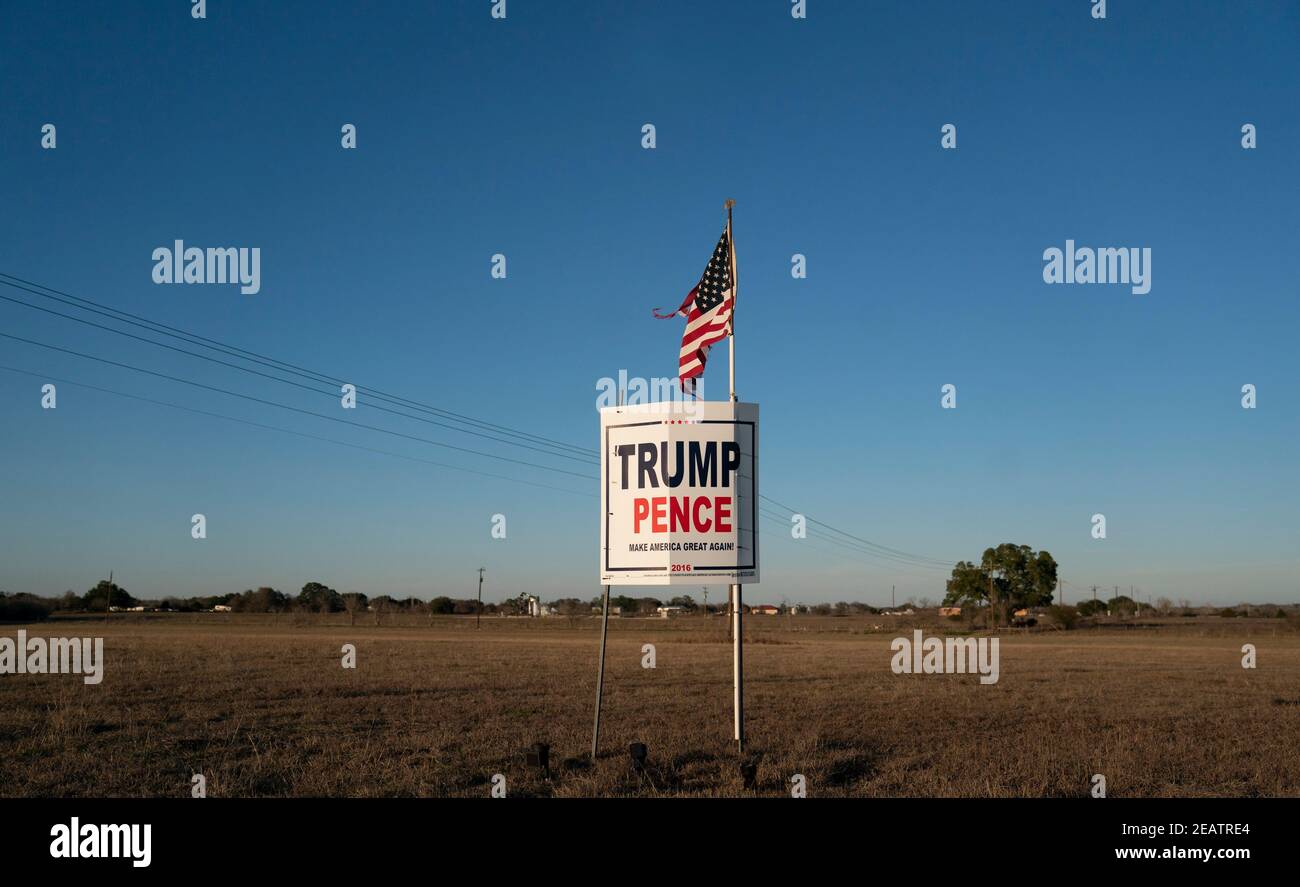 A farmer outside of Smithville in Bastrop County, TX flies a slightly tattered American flag over a Trump-Pence campaign sign three months after the November election in which the Republican ticket lost. Opinion polls show that many rural Texans still refuse to accept a Democratic presidential victory. ©Bob Daemmrich Stock Photo