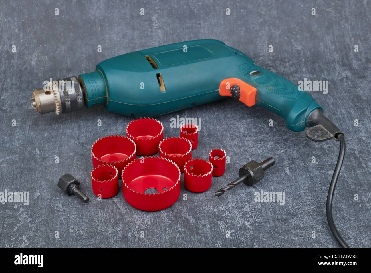 Close up set saw crown and electric drill, on gray table backgro Stock Photo