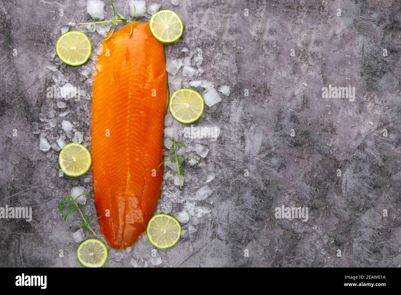 Fresh raw salmon fish steak with spices on ice over dark stone ...