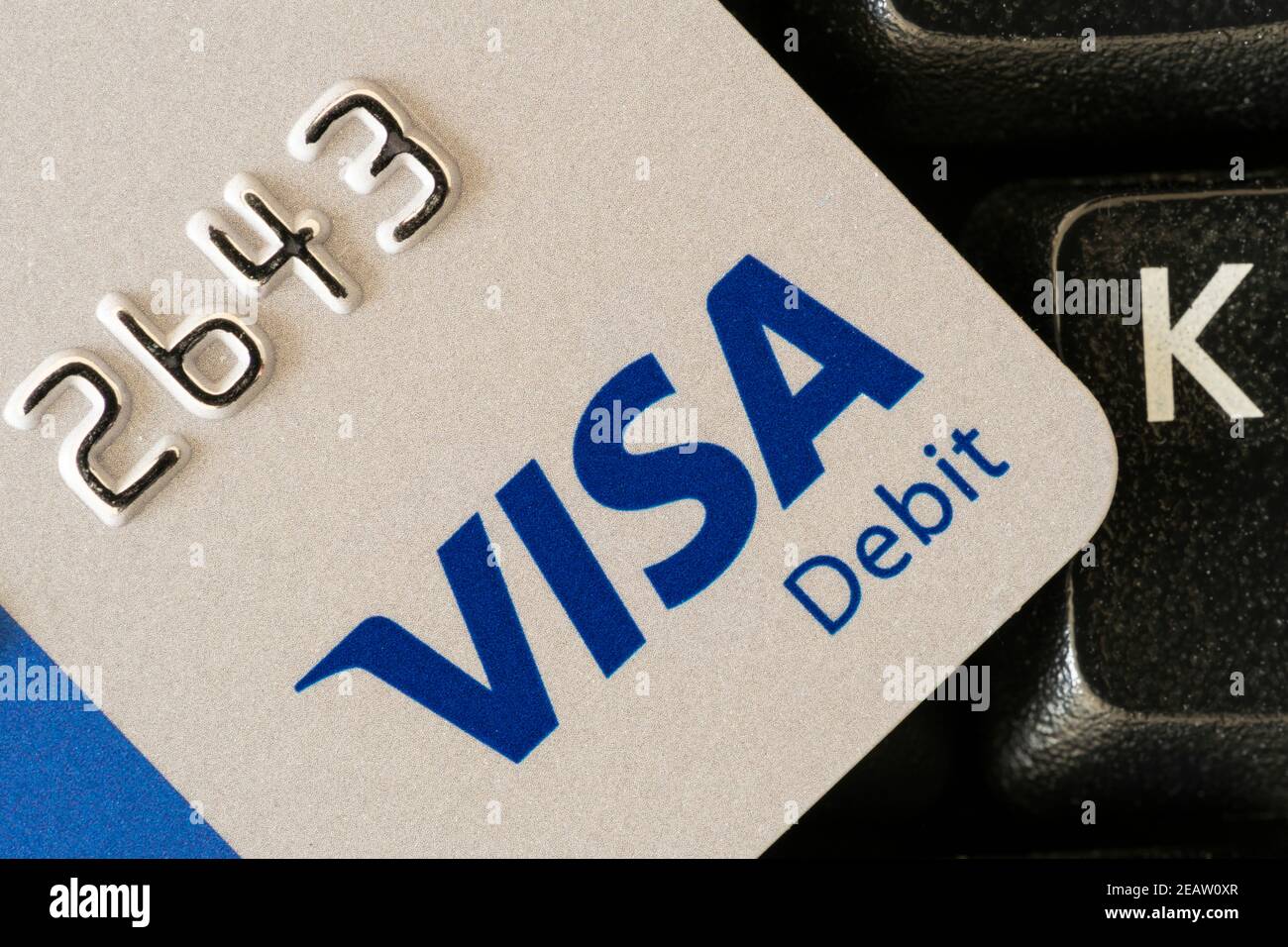 A closeup of the corner of a UK visa debit card resting on a keyboard, showing the card number and the Visa Debit logo Stock Photo