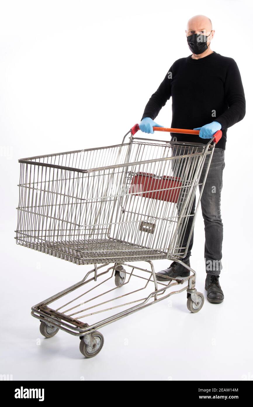 Man with mouth protection and hand gloves pushing a shopping cart, isolated on white background Stock Photo