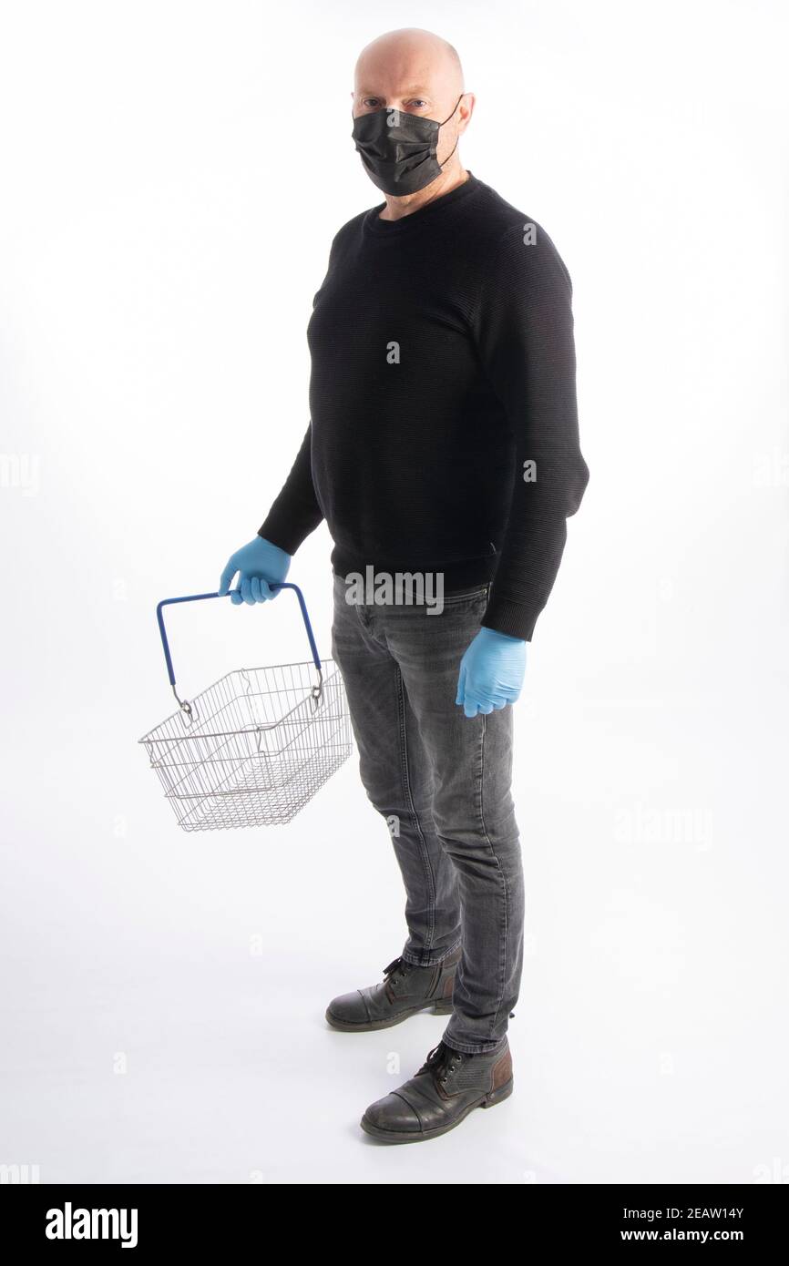 Man with mouth protection and hand gloves carrying a shopping basket, isolated on white background Stock Photo