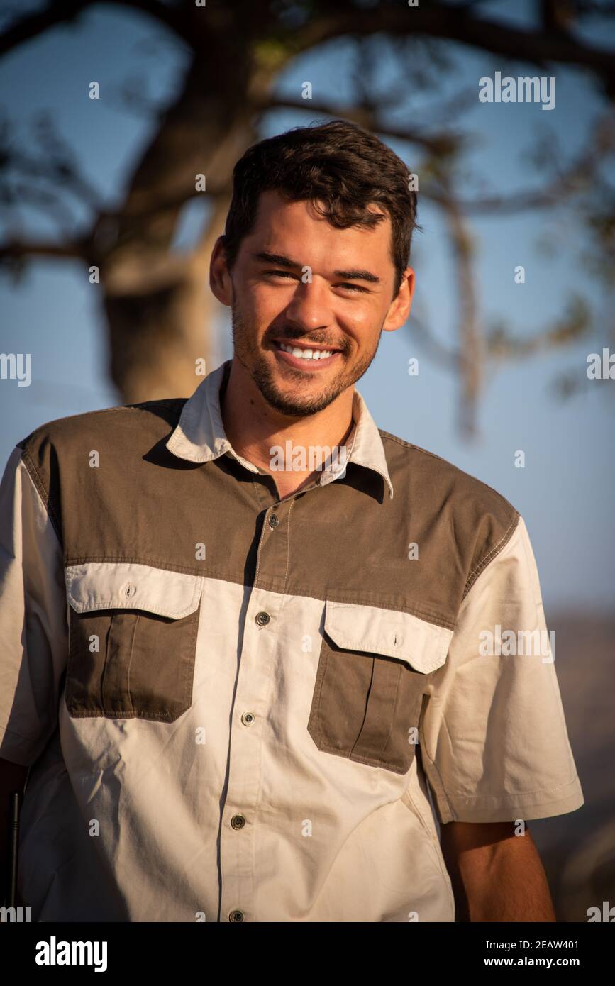 Close-up of smiling safari guide near tree Stock Photo