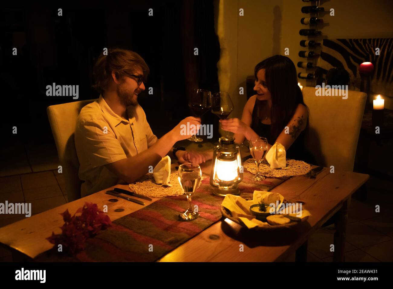 Couple clink glasses at table by candlelight Stock Photo Alamy
