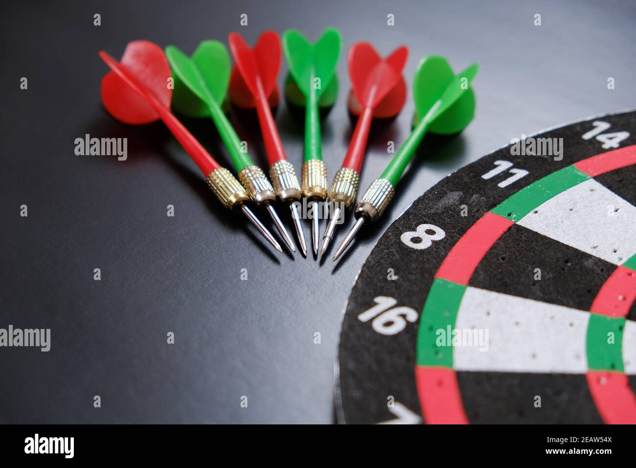 dartboard and red, green and yellow darts on a black background Stock Photo