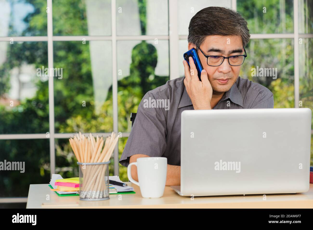 senior businessman sitting on desk office he using his mobile phone