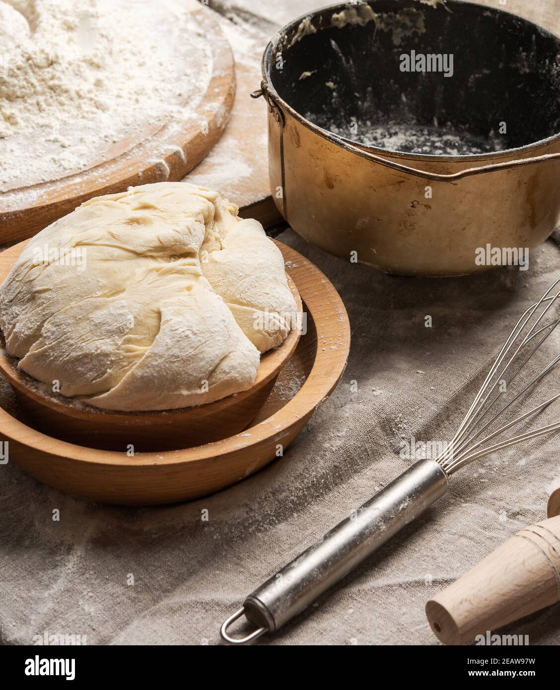 kneaded dough made of white wheat flour in a wooden plate and a metal