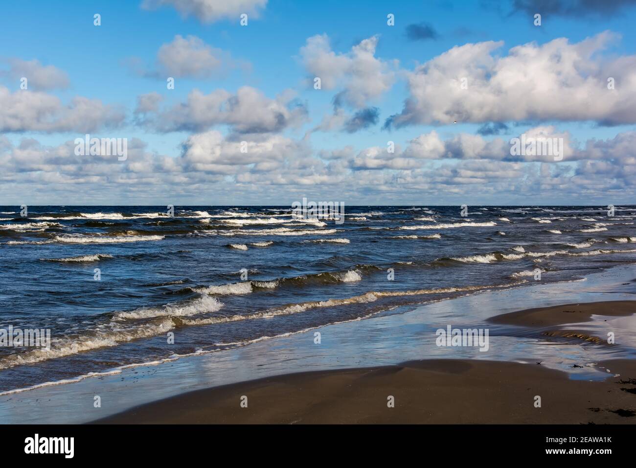 White cumulus clouds in sky over wavy Baltic sea water landscape. Many ...