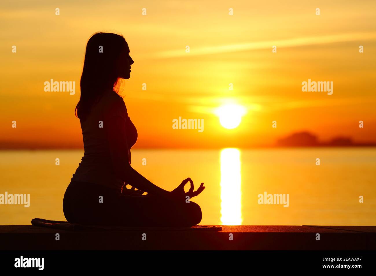 Silhouette of a woman doing yoga exercise at sunset Stock Photo