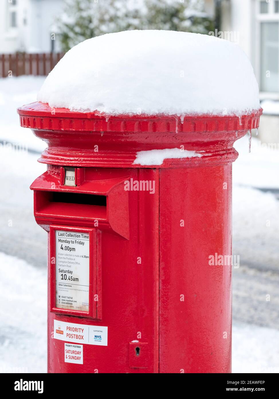 Snow covered red priority postbox Stoneyburn village, West Lothian. Stock Photo