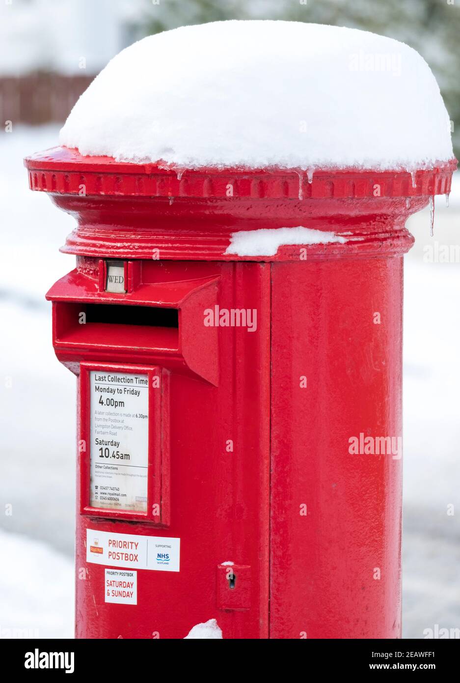 Snow covered red priority postbox Stoneyburn village, West Lothian. Stock Photo