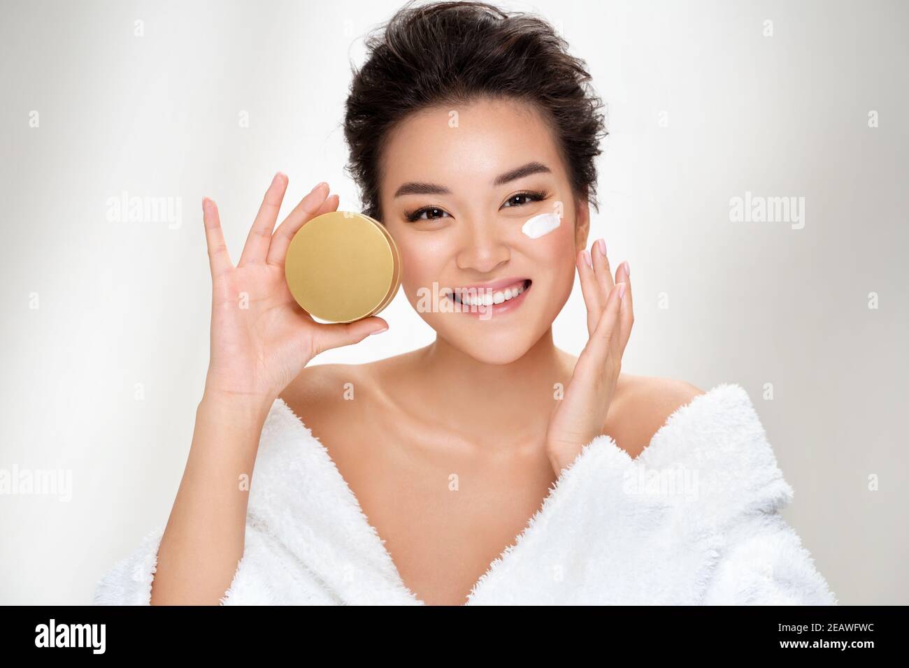 Beautiful woman applying moisturizer cream on her face. Photo of asian