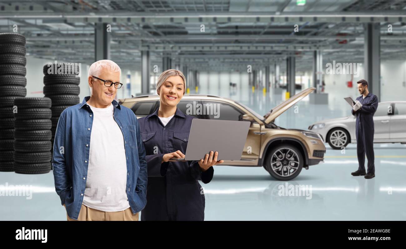 Mature man and a female auto mechanic looking at a laptop computer in a auto repair workshop Stock Photo