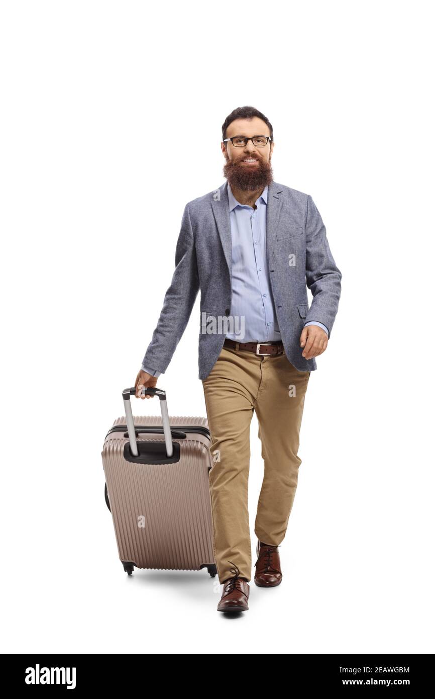 Full length portrait of a bearded man pulling a suitcase and walking towards the camera isolated on white background Stock Photo