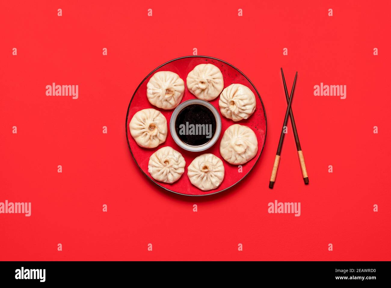 Bao dumplings on red plate with Chinese sauce, isolated on a red