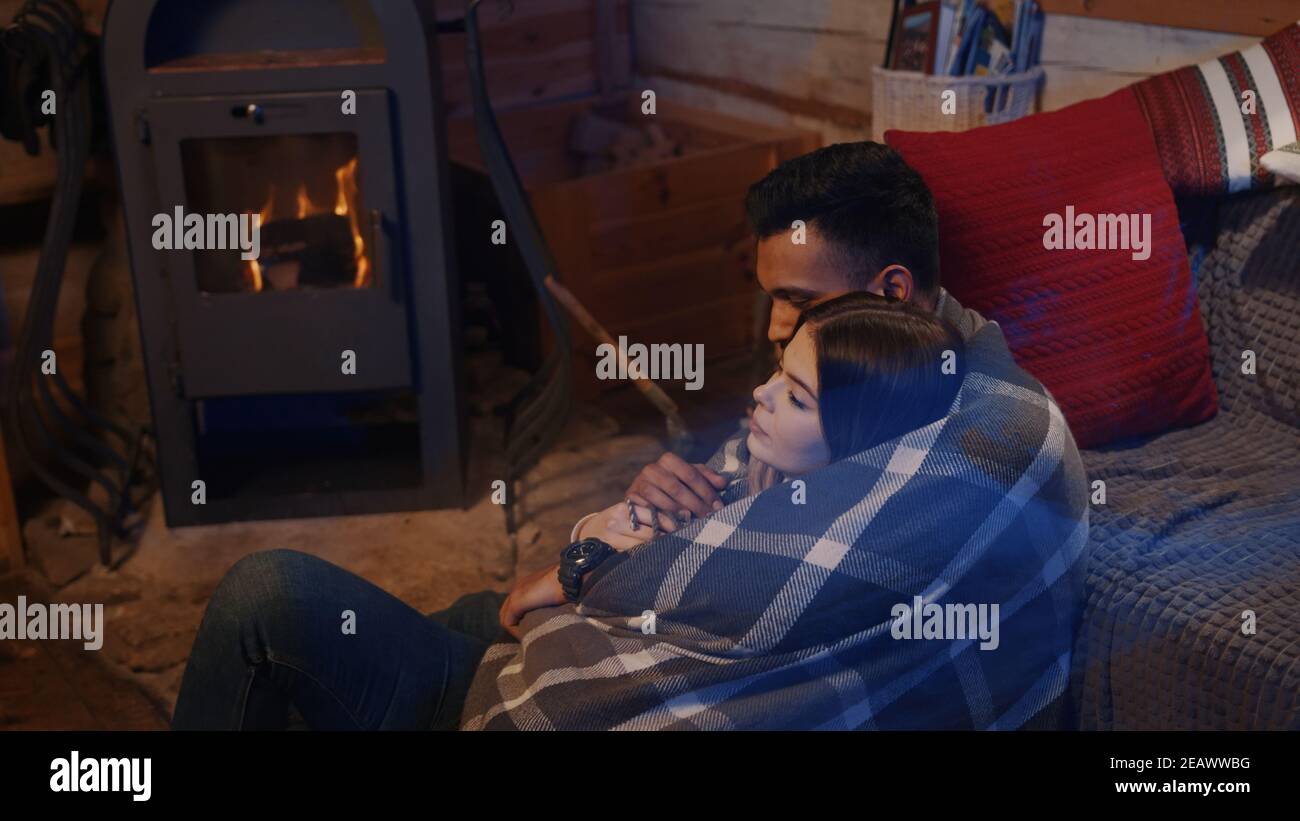 Couple sitting by the burning fireplace in a cozy house . High quality photo Stock Photo