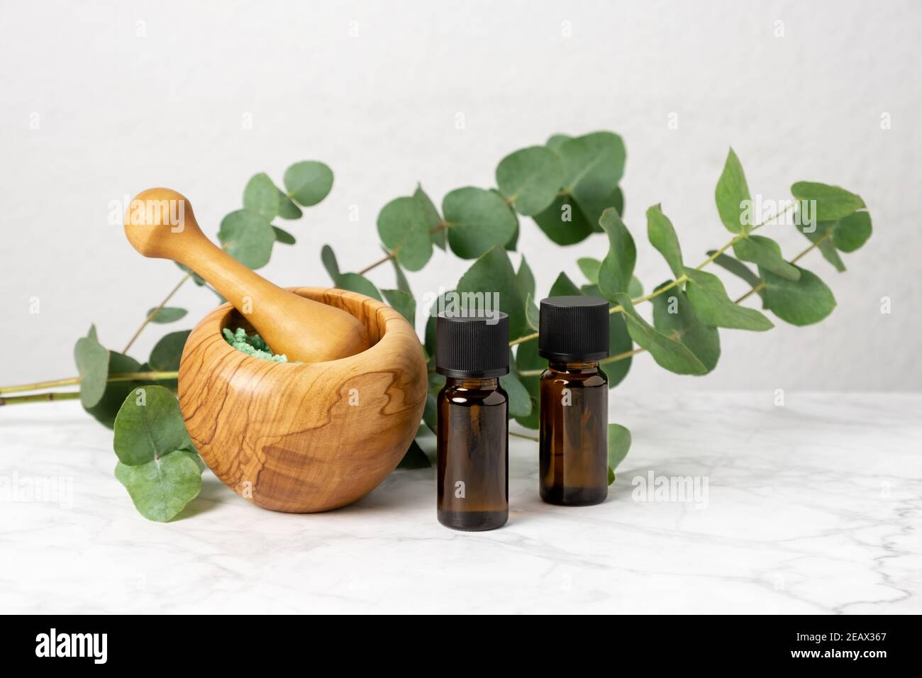 Natural aromatherapy with eucalyptus essential oil in bottles, aromatic bath salt and eucalyptus branch. Herbal spa, wellness and skin care products. Stock Photo