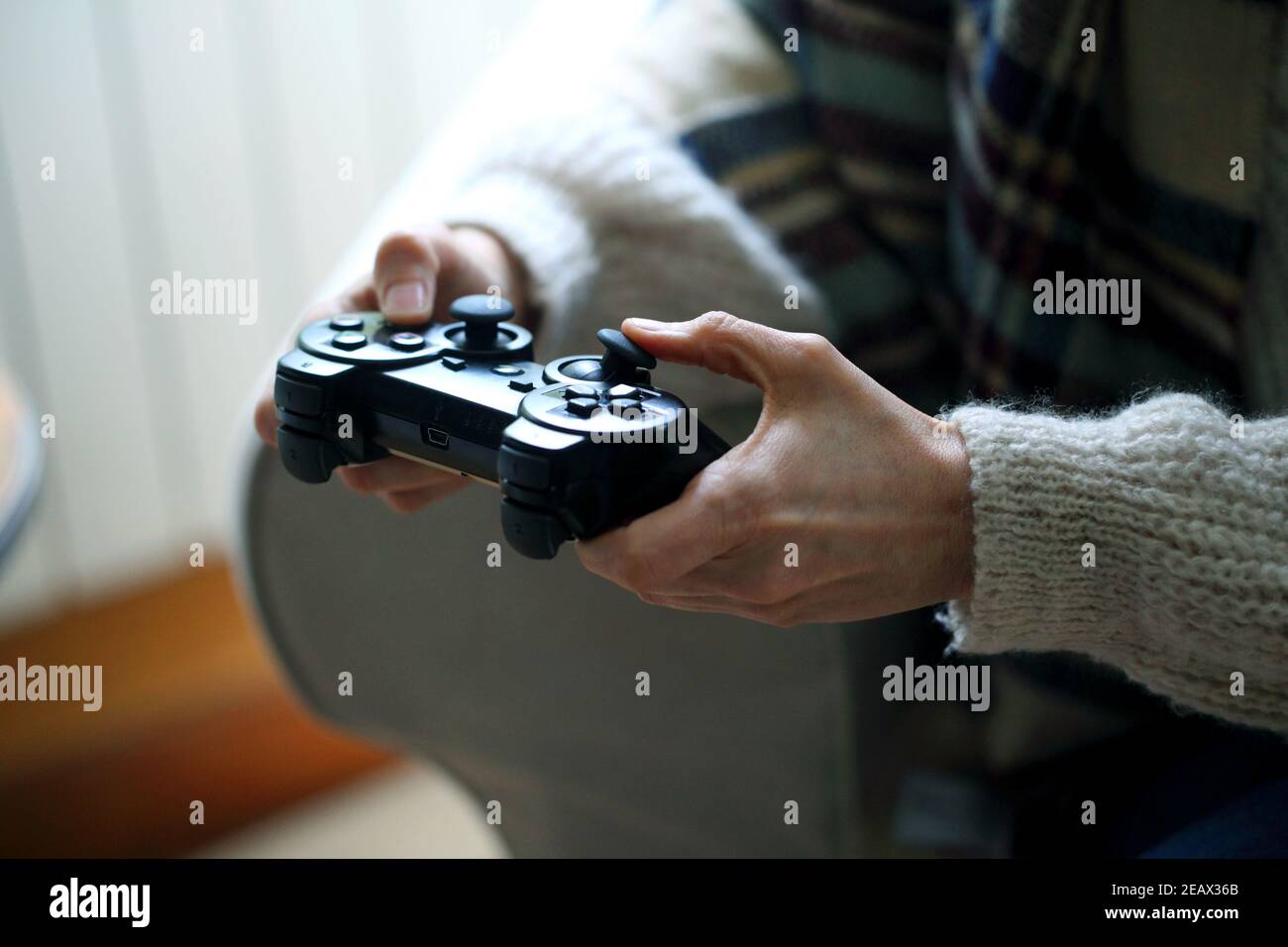 Closeup shot of a woman sitting on the couch holding a gaming controller Stock Photo