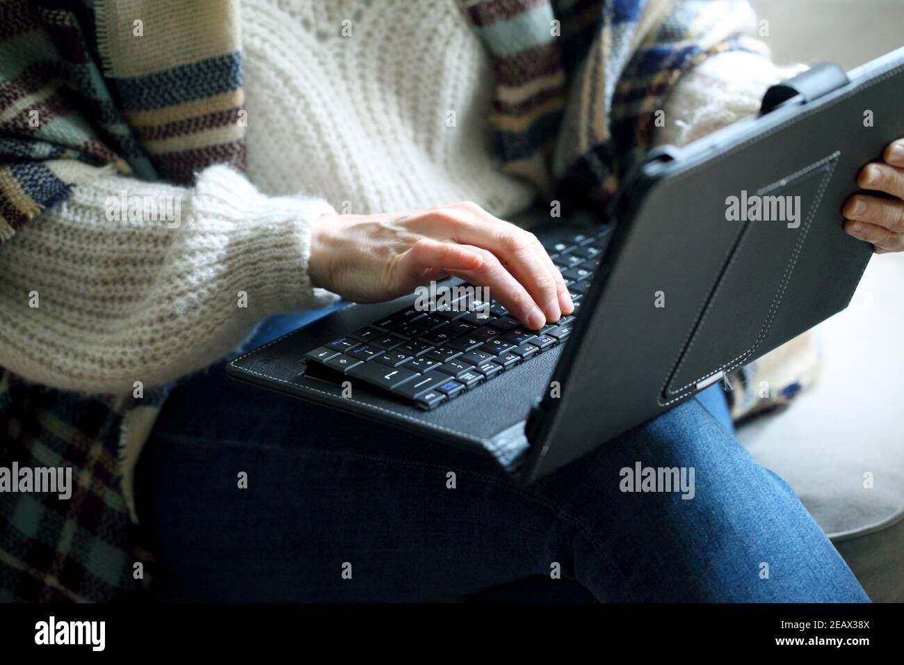 Closeup shot of a woman typing on a laptop in her lap Stock Photo