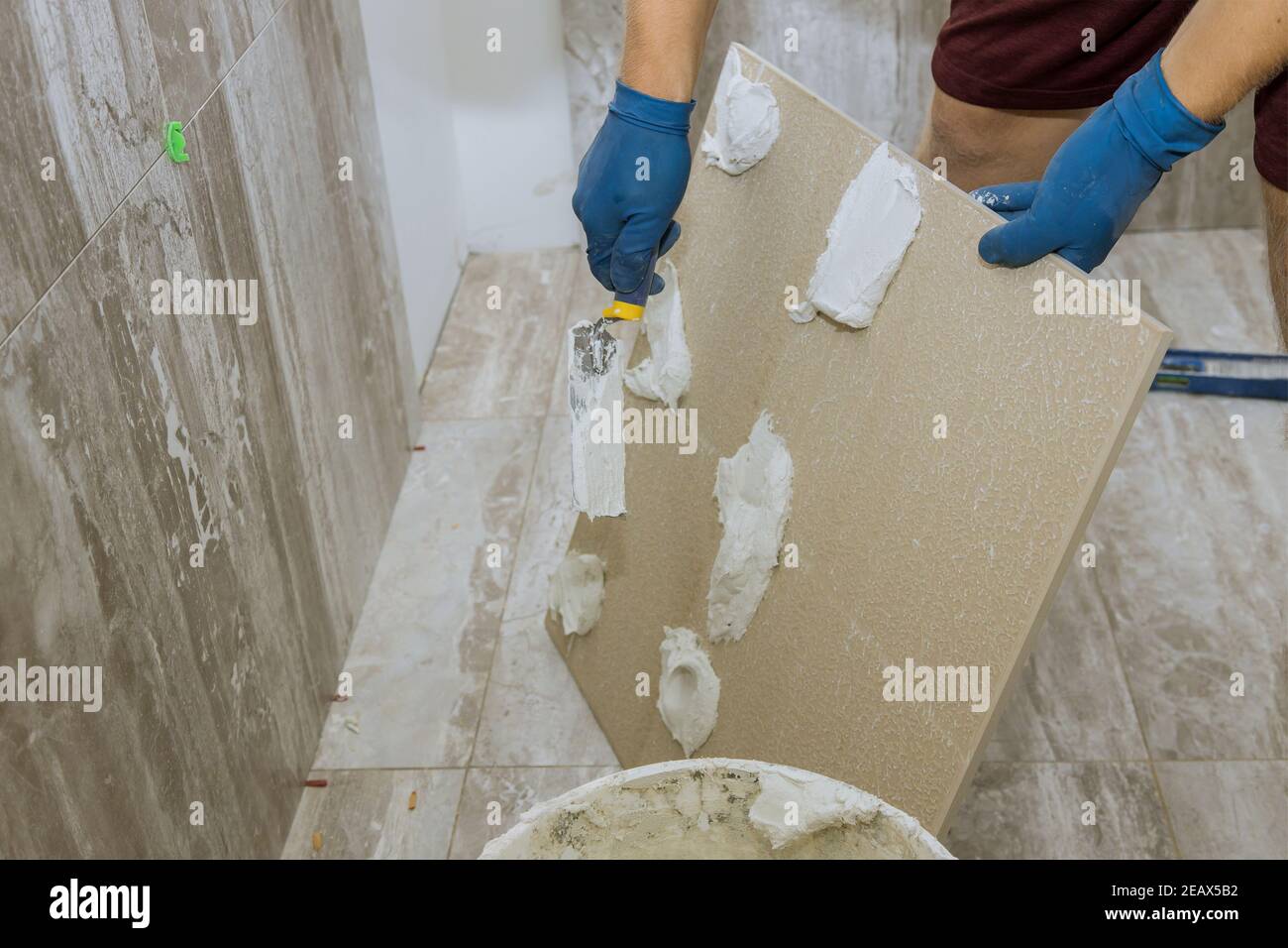 Spreading wet mortar before applying tiles on bathroom floor tile Stock
