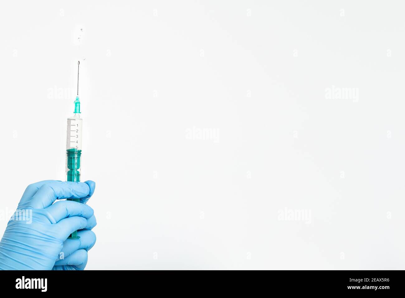 A doctor's hand in a medical glove holds a syringe with a needle to protect against the flu virus. Cvd vaccine. The concept of medicine vaccination Stock Photo