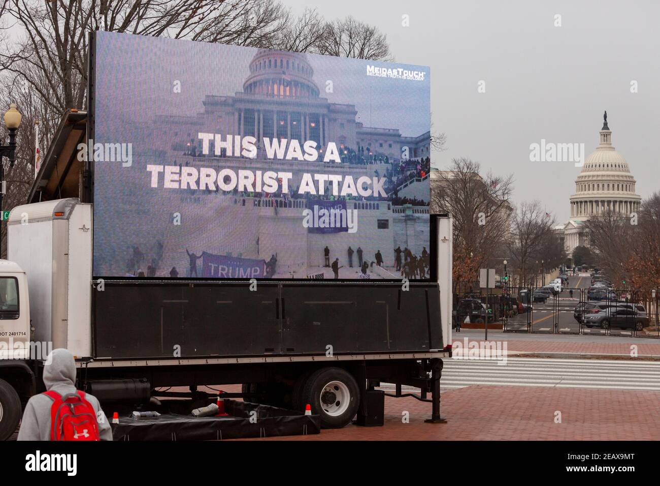 Washington, DC, USA, 10 February, 2021.  Pictured: A pedestrian watches a video urging conviction of Trump for incitement during the second day of his trial.  Meidas Touch media parked an advertisement truck just outside Capitol grounds playing videos urging Senators to convict Trump and to investigate and expel members of Congress who played a role.  Credit: Allison C Bailey/Alamy Live News Stock Photo