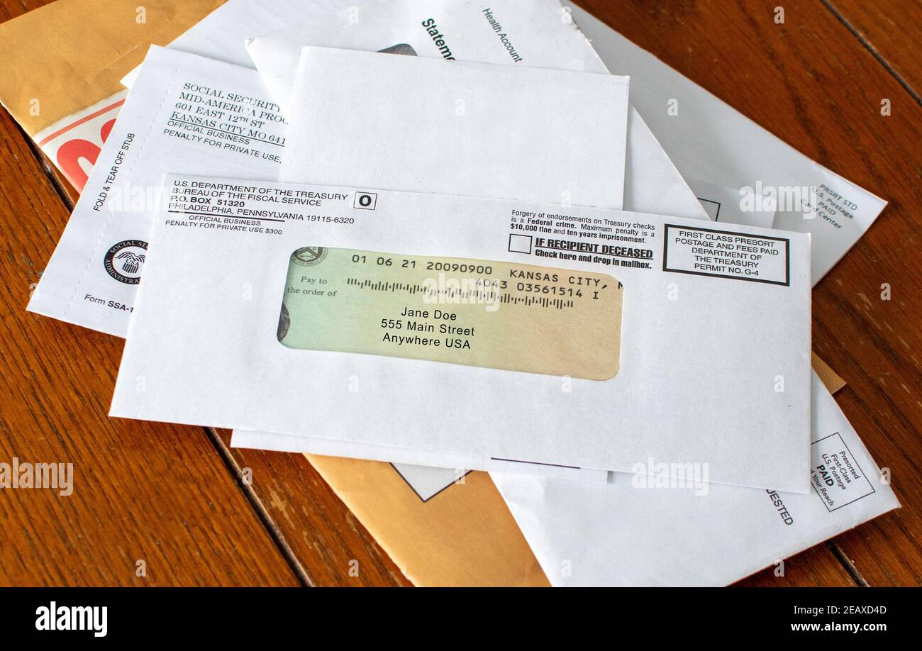 Stimulus check is shown on top of a stack of mail. the check is in the mail. Stock Photo