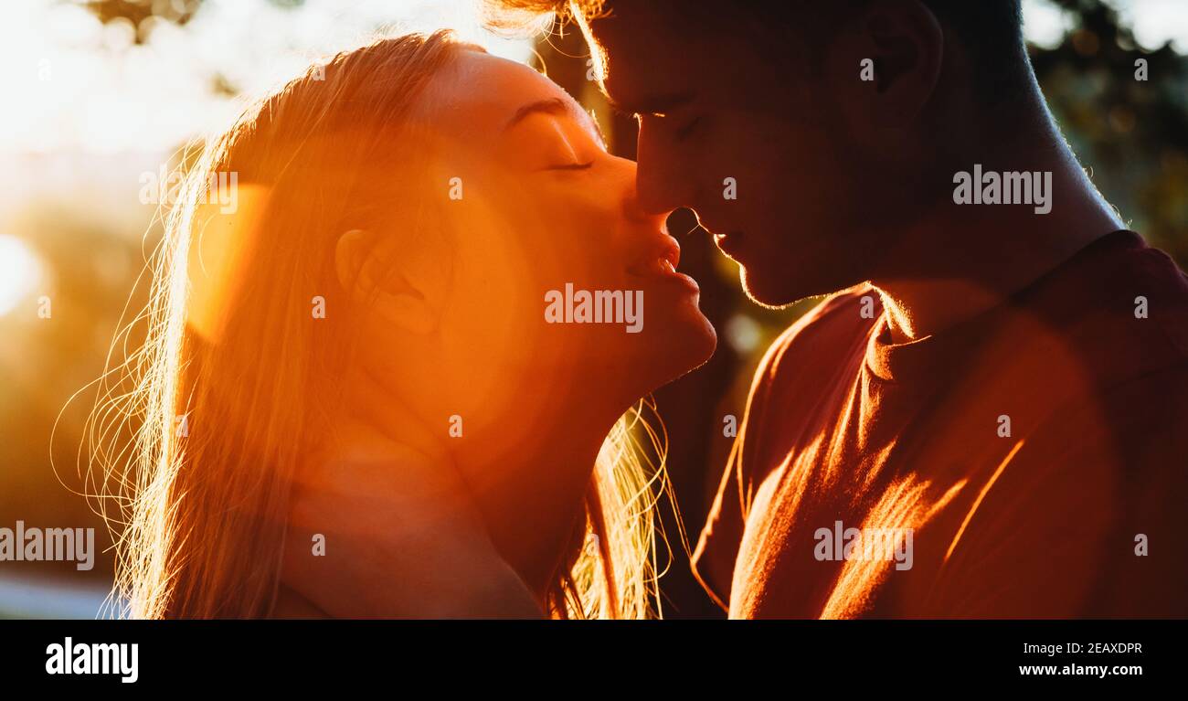 Close up photo of a caucasian couple kissing in the light of the sun ...