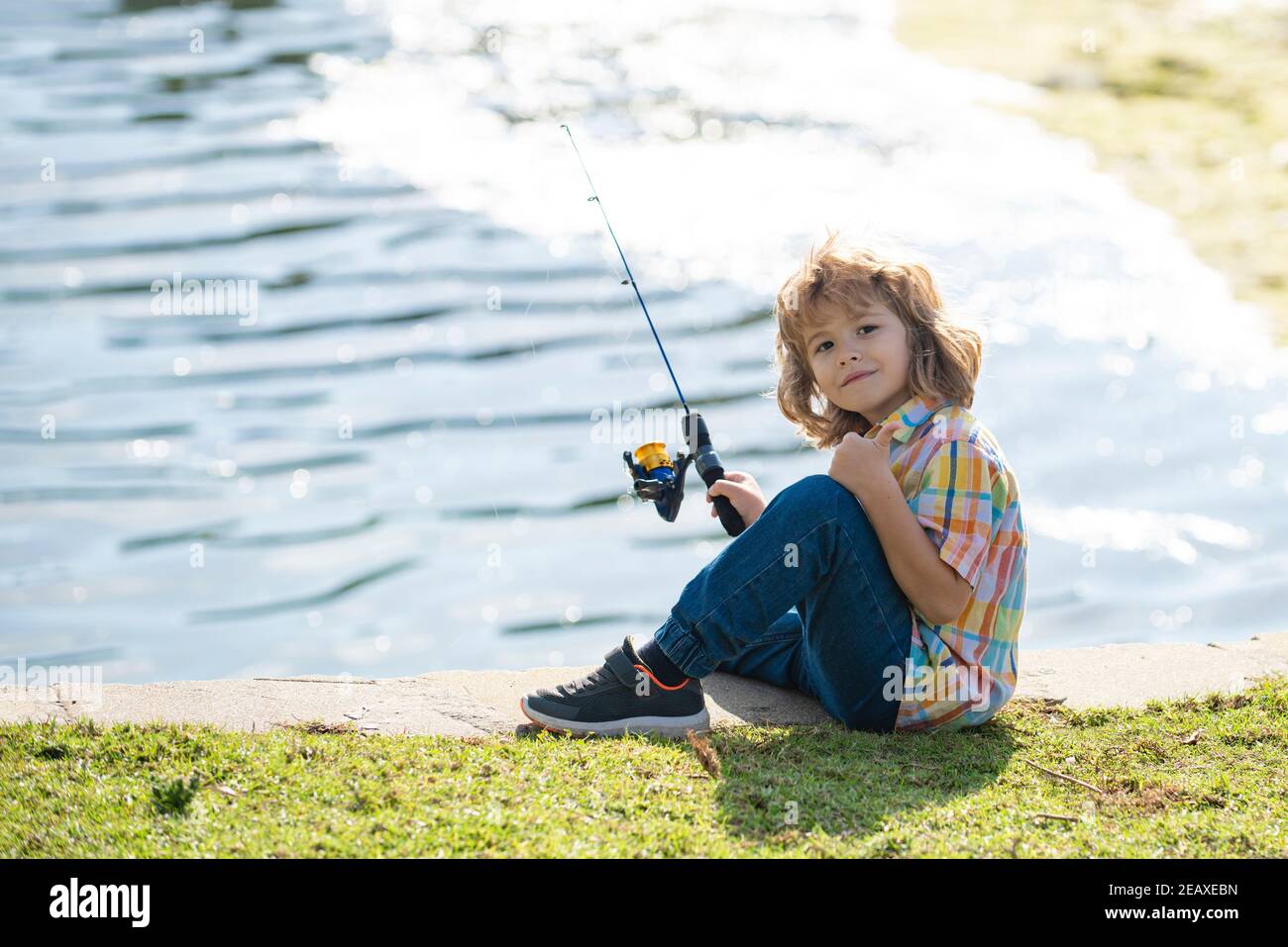 Kids hobby. Smiling child fishing on the lake. Boy with spinner at
