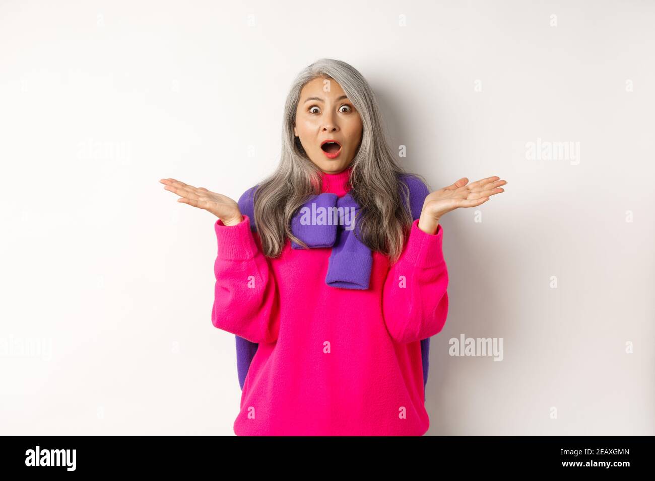 Surprised and amazed asian elderly woman spread hands sideways in 