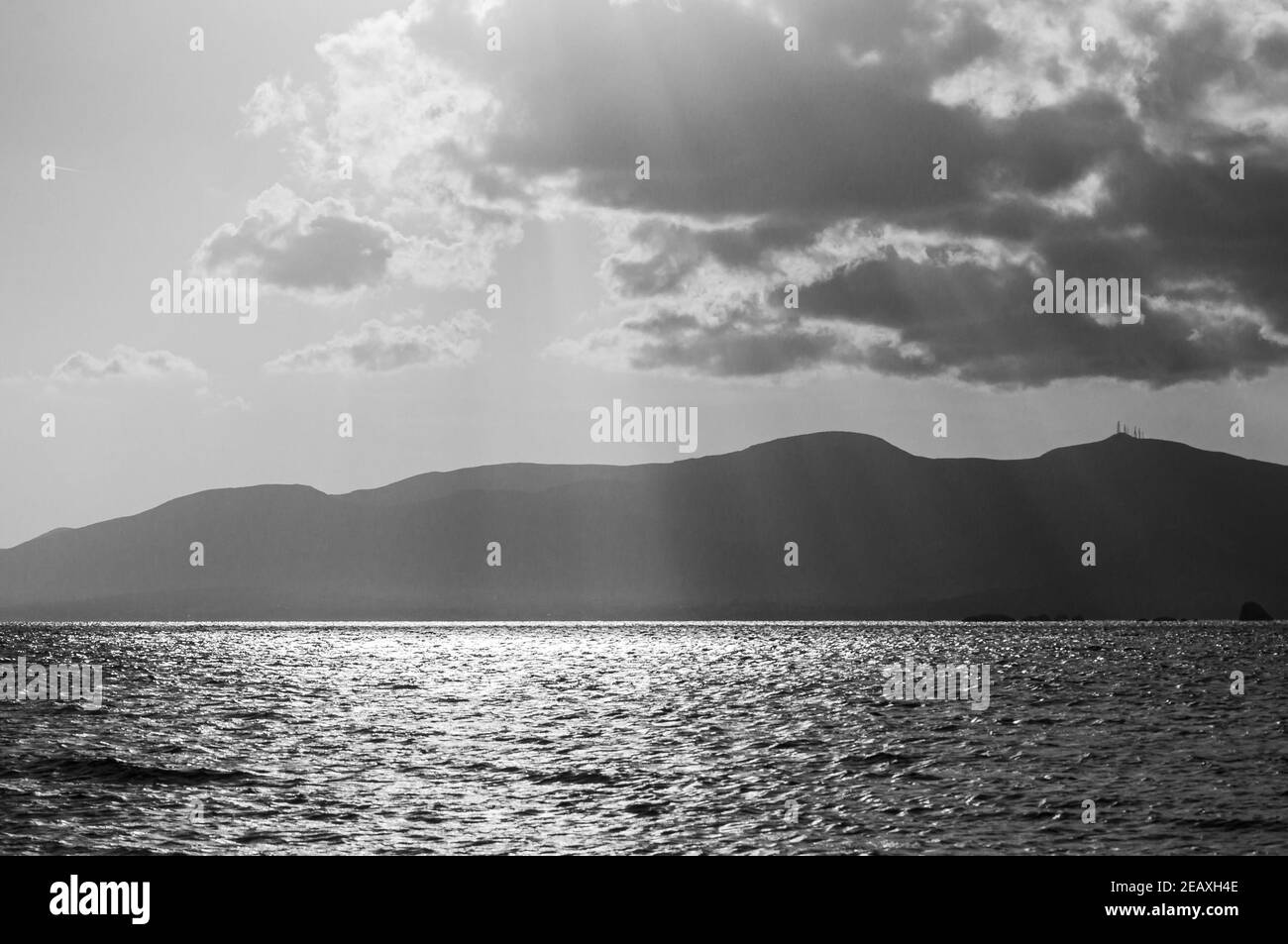 Wonderful sunlight in black and white - holiday photo with an awesome sunset over the sea, the warm sun is shining through the clouds. Stock Photo