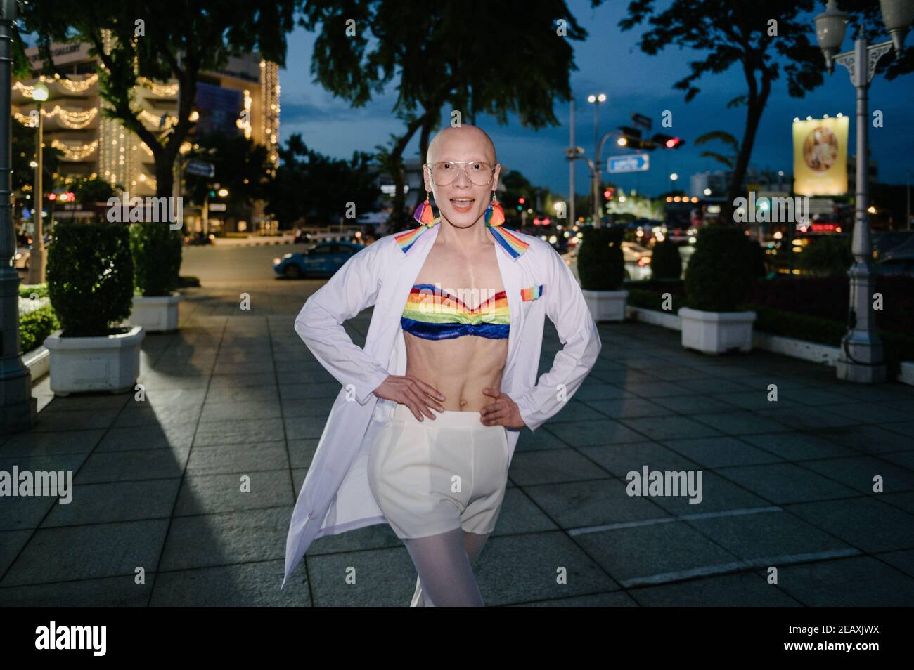 An Asian Queer person wearing a medical doctor white uniform with rainbow colors items to protest against discrimination of LGBTQ community members. Stock Photo