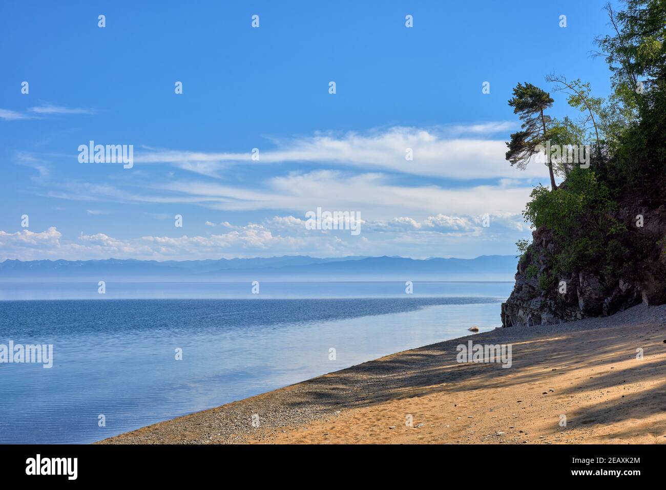 The sandy shore of Lake Baikal. Beautiful landscape with a distant view of the mountain range on the opposite shore. June. Irkutsk region. Eastern Sib Stock Photo