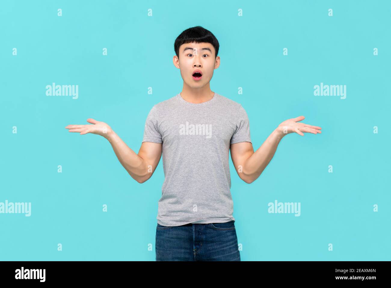 Shocked young Asian man frustratedly questioning and being doubtful isolated on light blue background Stock Photo
